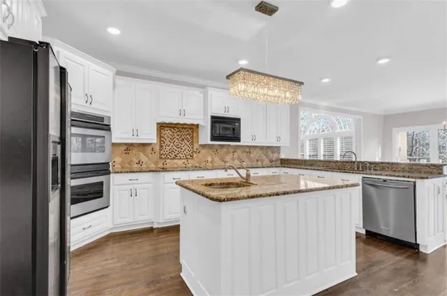 a kitchen with stainless steel appliances granite countertop a sink and dishwasher a refrigerator with wooden floor