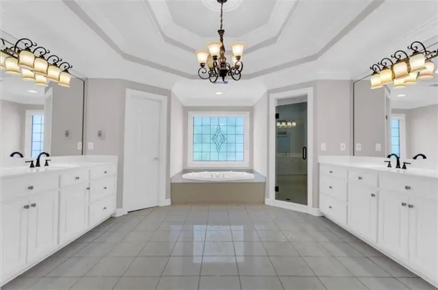 a spacious bathroom with a granite countertop sink a large mirror and a bathtub