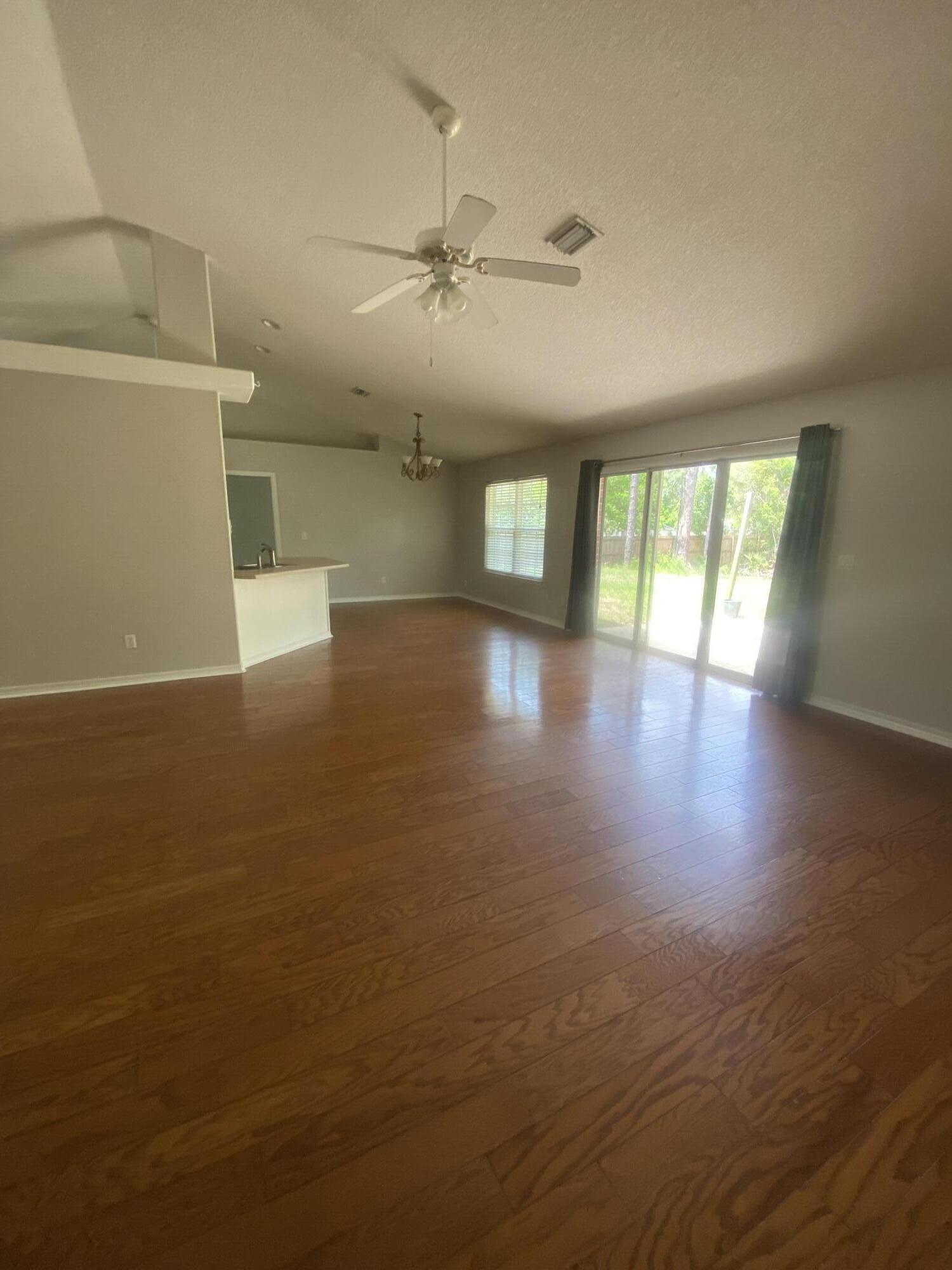 6568 Fern Street Navarre, FL 32566 - Photo 2 of 10 an empty room with wooden floor and windows
