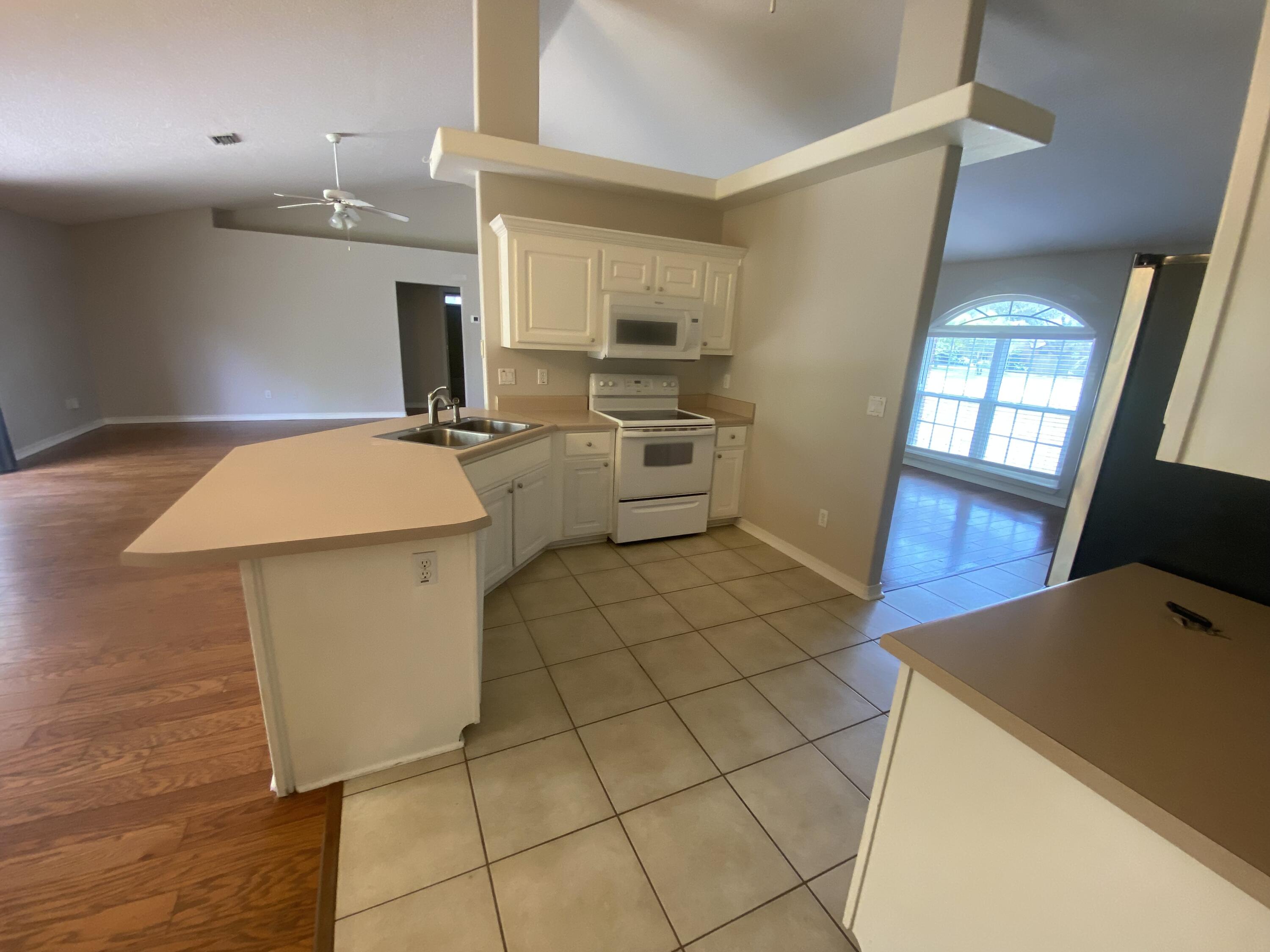 6568 Fern Street Navarre, FL 32566 - Photo 5 of 10 a kitchen with a sink a stove and cabinets