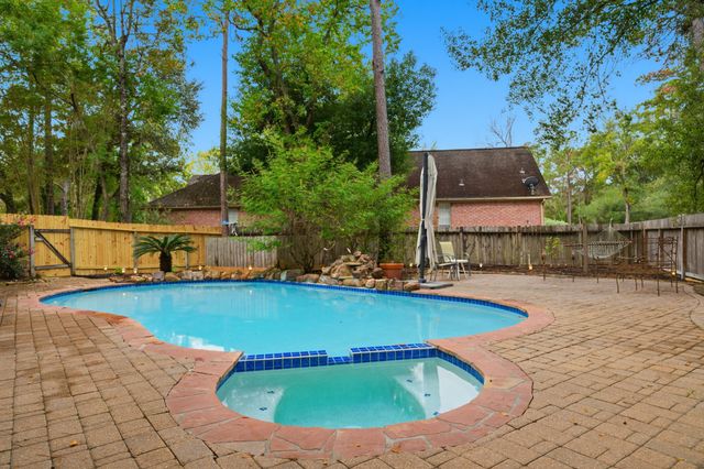 a view of swimming pool with seating space and trees in the background