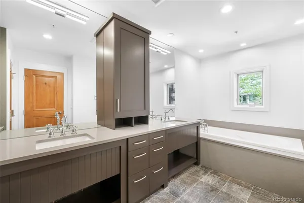 a bathroom with a sink double vanity granite tub and a mirror