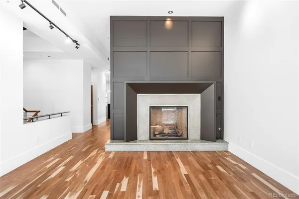 a view of an empty room with wooden floor and a fireplace