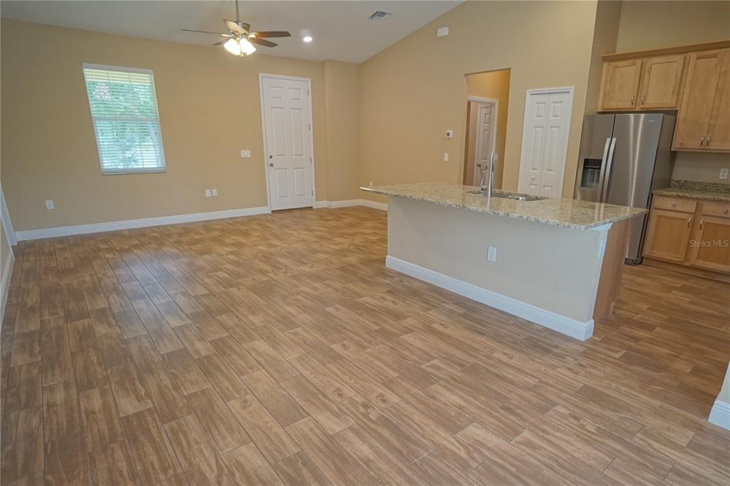 3525 West Ballast Point Boulevard Tampa, FL 33611 - Photo 16 of 25 an empty room with wooden floor and a kitchen