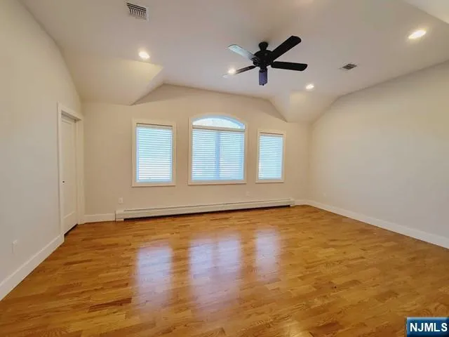 an empty room with wooden floor ceiling fan and windows