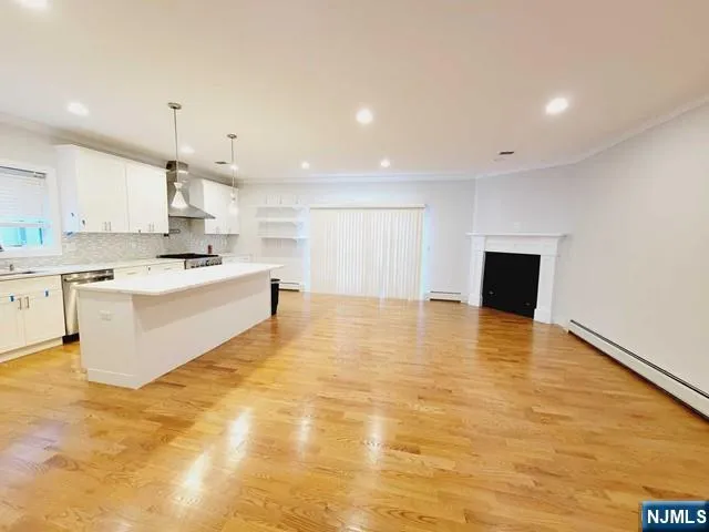 a large white kitchen with kitchen island a sink wooden floor and a counter top space