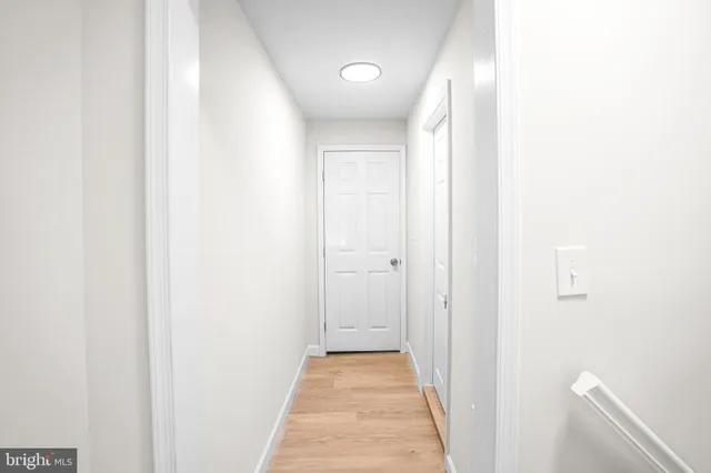 a view of a hallway with wooden floor and a bathroom