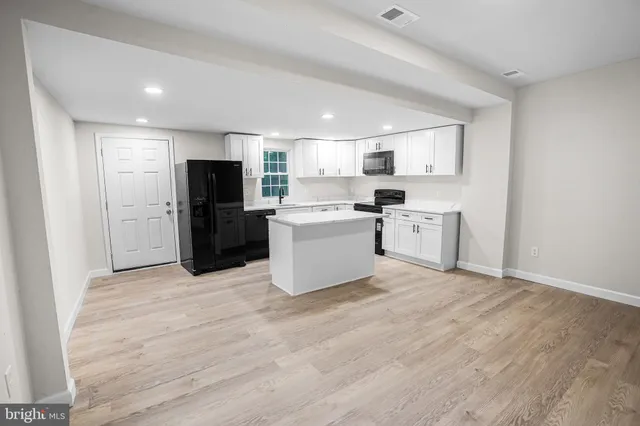 a kitchen with a refrigerator a stove top oven and white cabinets