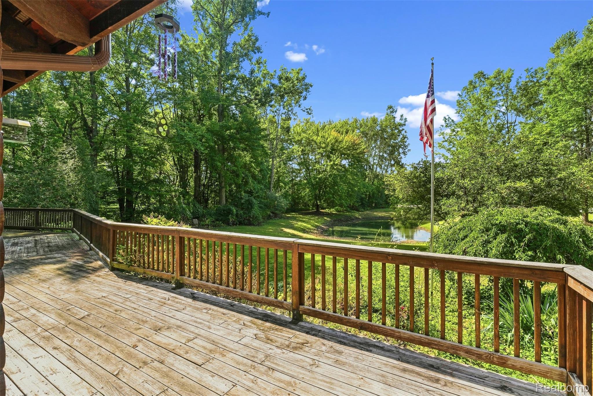 8340 North Nichols Road Flushing, MI 48433 - Photo 9 of 62 Expansive wooden deck with wooden railing overlooking a pond and mature trees