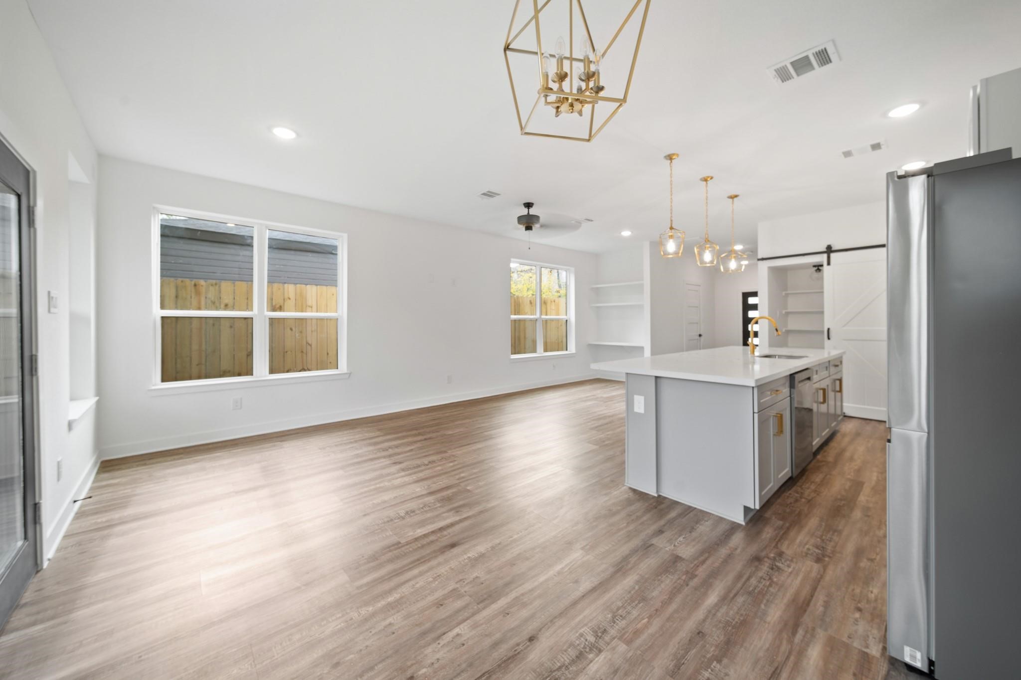 5813 England Street, Unit A Houston, TX 77021 - Photo 8 of 18 Bright, open-concept living space with sleek hardwood floors, modern lighting, and a spacious kitchen featuring a large island and stainless steel appliances.