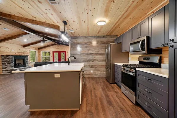 a kitchen with stainless steel appliances granite countertop a sink a stove and a wooden floors