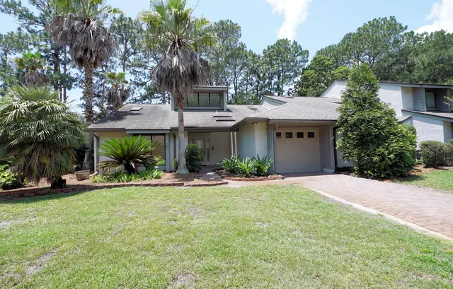 a front view of a house with a yard and palm trees