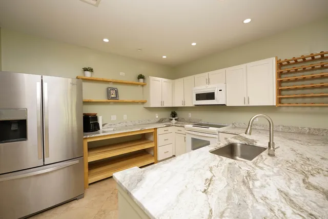 a kitchen with granite countertop a refrigerator and a sink