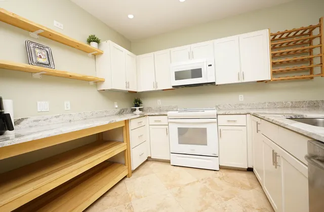 a kitchen with granite countertop white cabinets and white appliances