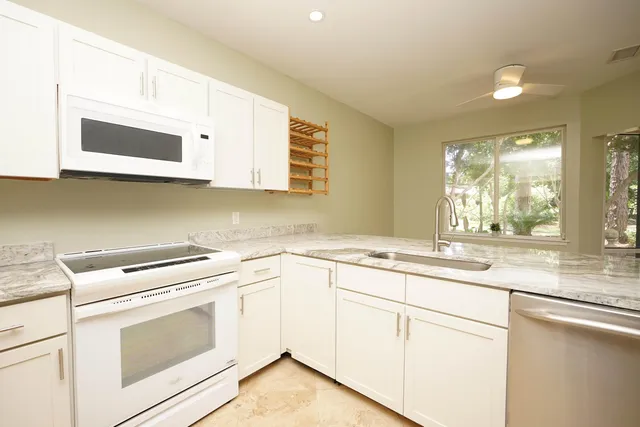 a kitchen with granite countertop white cabinets and white appliances