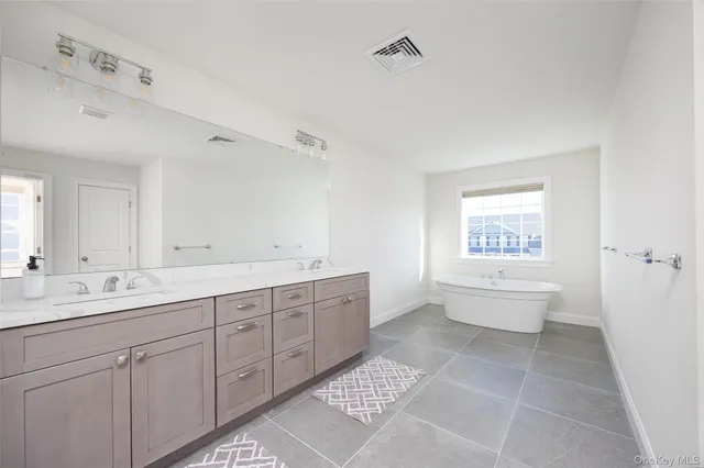 a spacious bathroom with a bathtub sink mirror and toilet