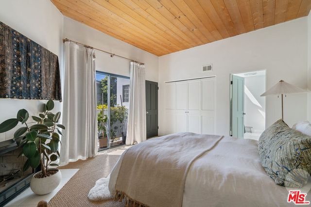 a bedroom with a bed potted plant with the view of bathroom