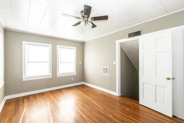 a view of empty room with wooden floor and fan