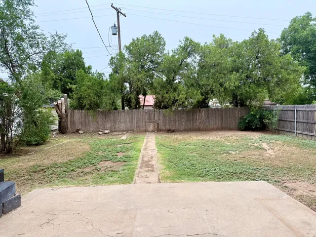 a view of a backyard with large tree and wooden fence