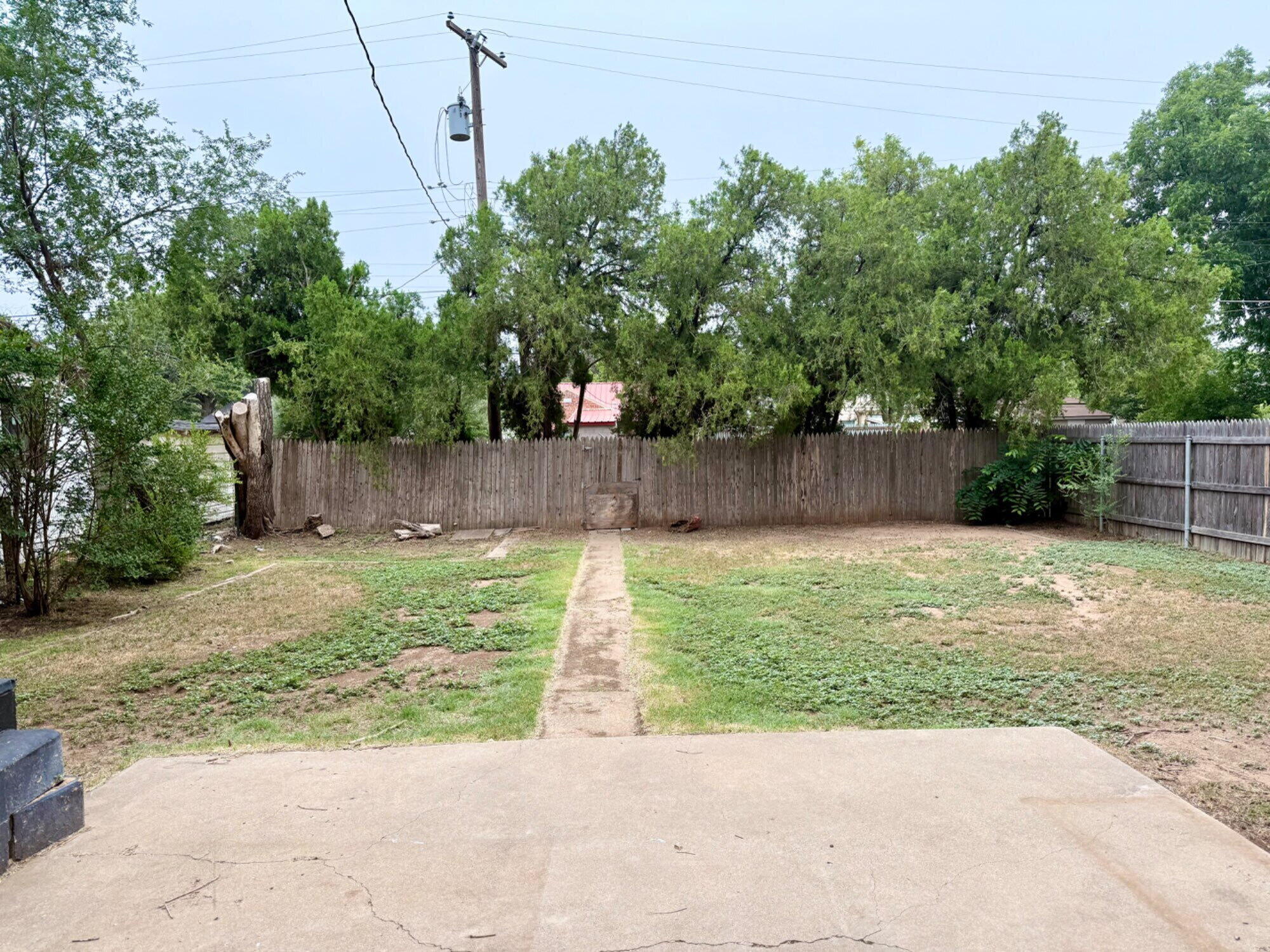 2417 25th Street Lubbock, TX 79411 - Photo 24 of 25 a view of a backyard with large tree and wooden fence