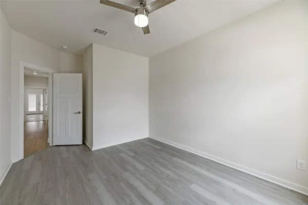 an empty room with wooden floor ceiling fan and windows