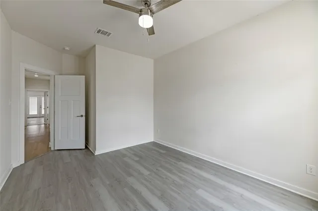 an empty room with wooden floor ceiling fan and windows