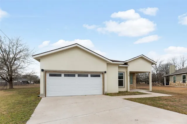 a front view of a house with a garden and trees