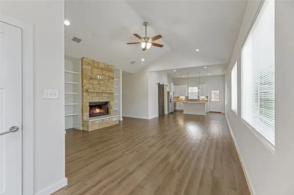 a view of a livingroom with wooden floor a ceiling fan and windows