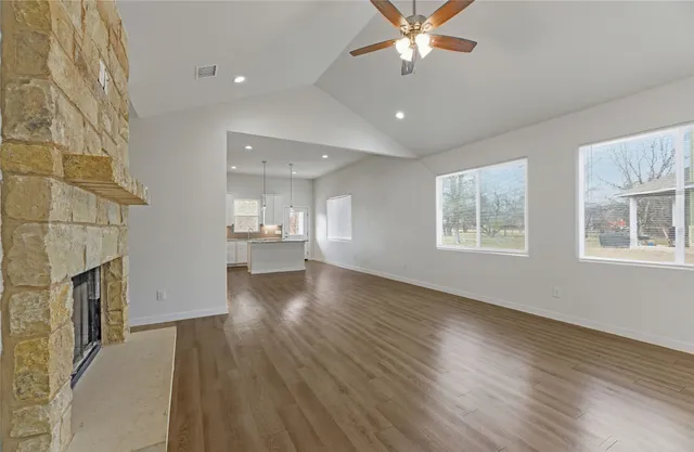 a view of an empty room with a window and wooden floor