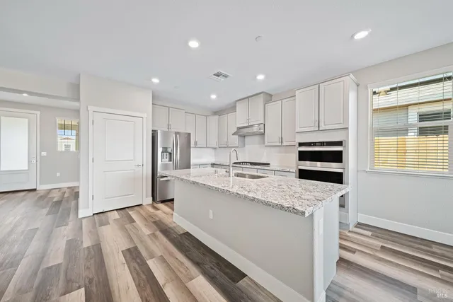 a kitchen with stainless steel appliances granite countertop a refrigerator and a sink
