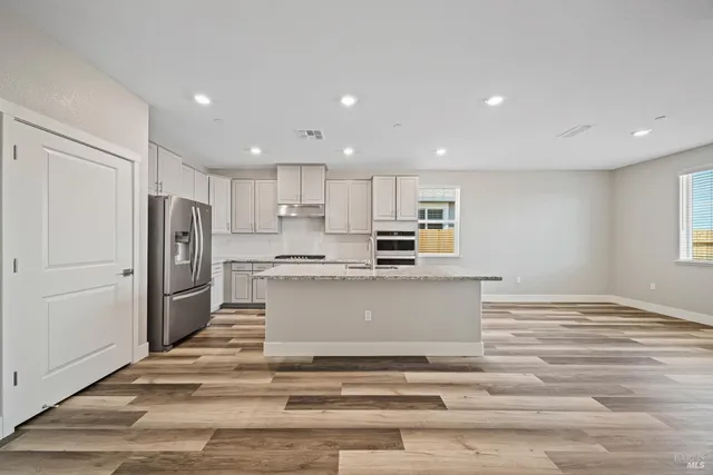 a view of kitchen with refrigerator cabinets and wooden floor