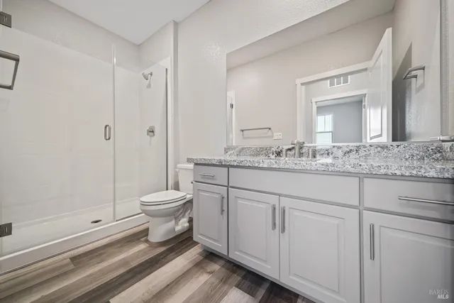 a bathroom with a granite countertop toilet a sink and a mirror