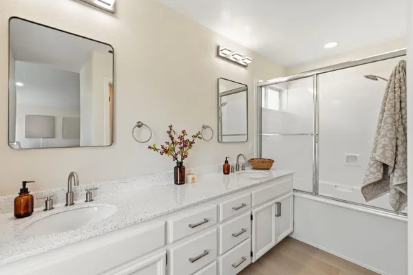 a bathroom with double vanity sink a mirror and shower