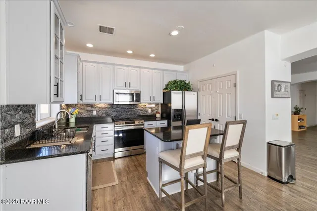 a kitchen with stainless steel appliances granite countertop a table chairs and a refrigerator