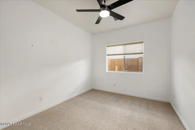 an empty room with a window and ceiling fan