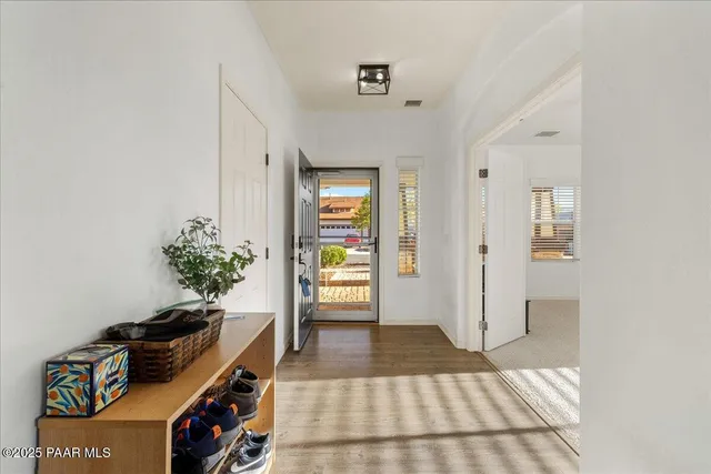 a view of a hallway to a livingroom with wooden floor and a potted plant