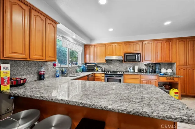 a kitchen with stainless steel appliances granite countertop sink microwave and window