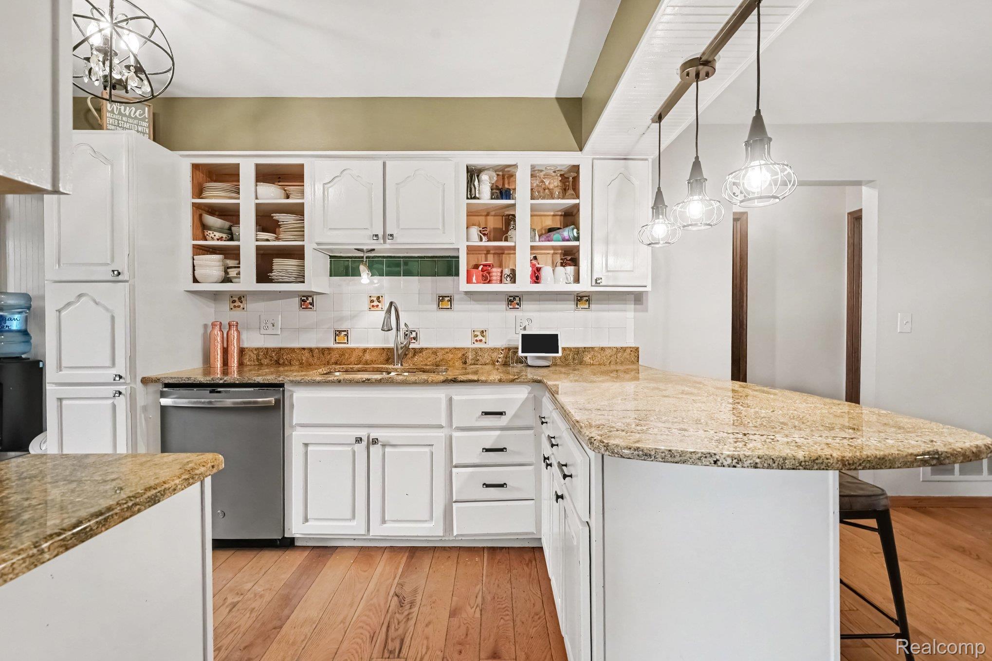107 Michelle Drive Romeo, MI 48065 - Photo 12 of 30 Kitchen featuring white cabinetry, a light-toned patterned countertop, a stainless steel dishwasher, a single-basin sink with a gooseneck faucet, and wood-finish flooring