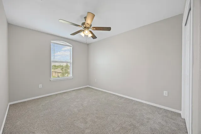 an empty room with a window and a fan