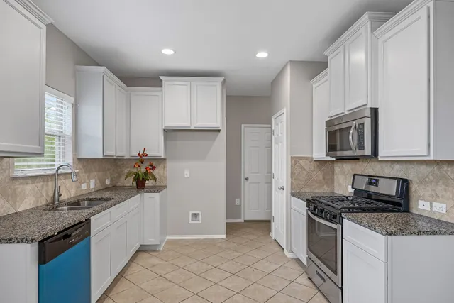 a large kitchen with granite countertop white cabinets and a large window