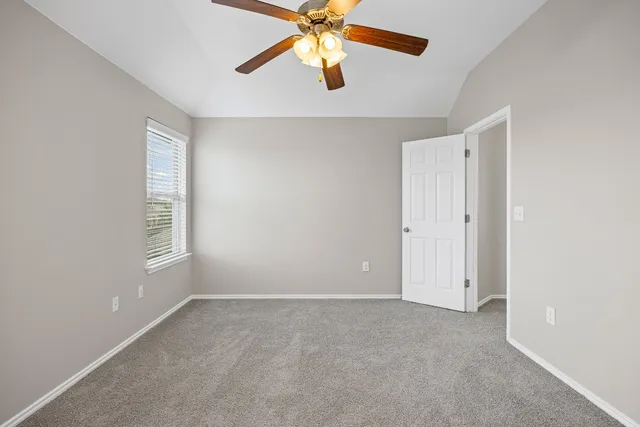 an empty room with chandelier fan and windows