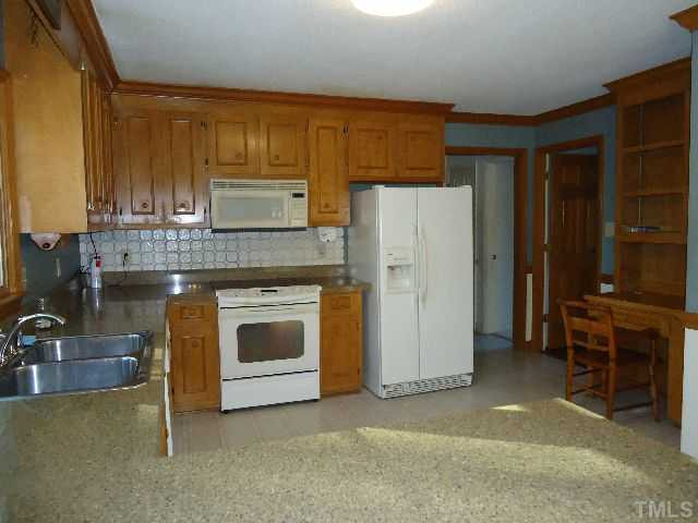 5610 Red Coach Road Durham, NC 27712 - Photo 8 of 16 a kitchen with granite countertop a refrigerator and a stove top oven