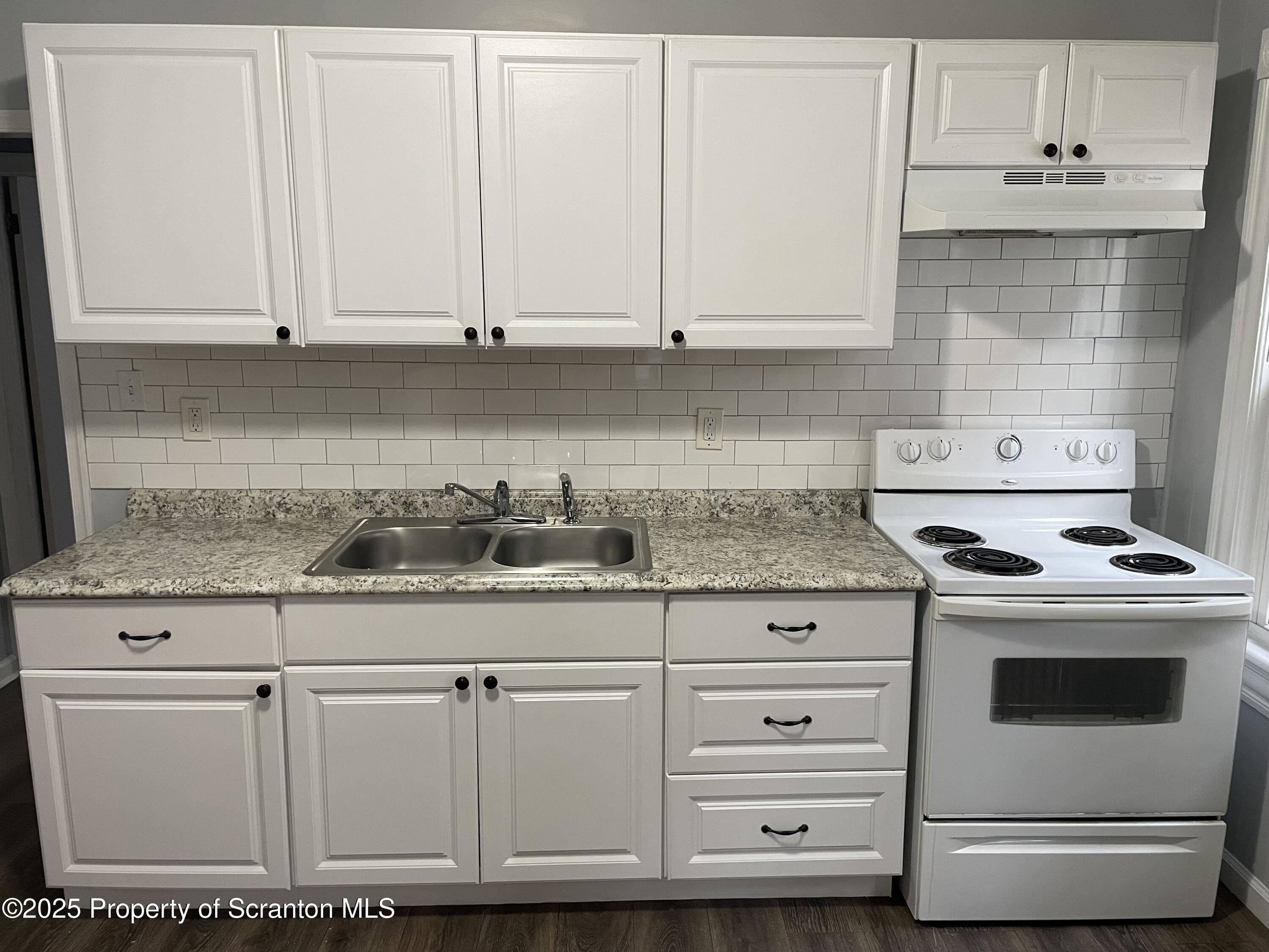 1309 Clay Avenue, Unit 1 Dunmore, PA 18510 - Photo 5 of 6 a kitchen with granite countertop white cabinets and white appliances