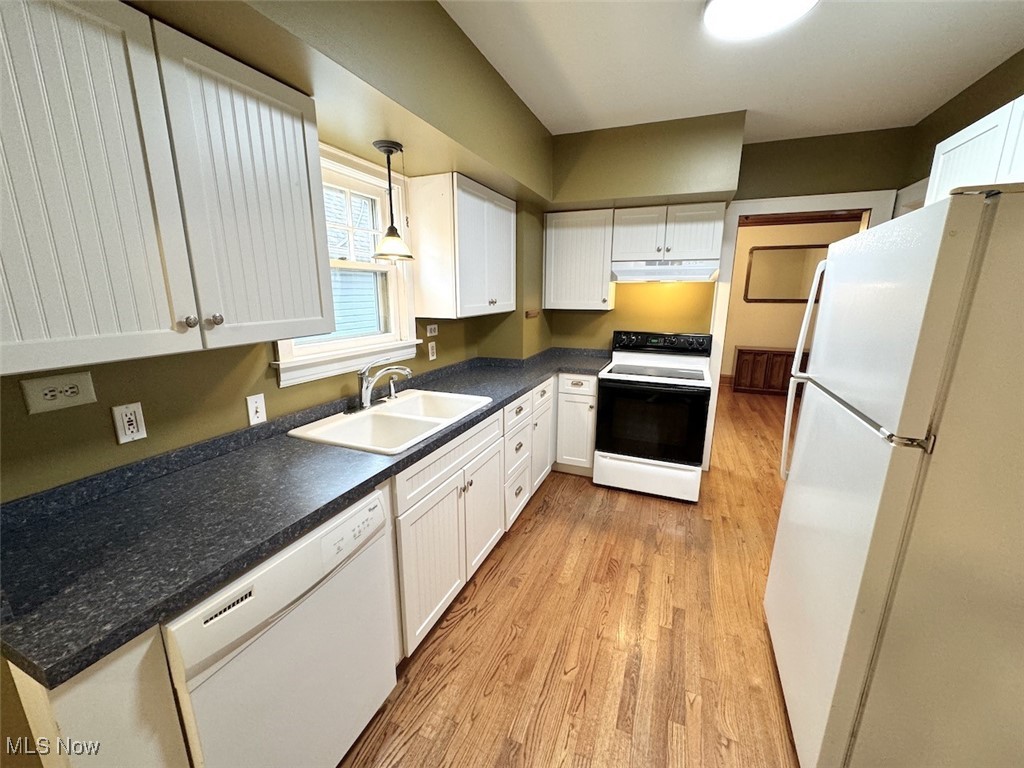 1011 Rushleigh Road Cleveland, OH 44121 - Photo 8 of 27 Kitchen with sink, white appliances, decorative light fixtures, white cabinetry, and light hardwood flooring