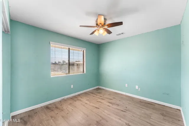 an empty room with wooden floor fan and windows