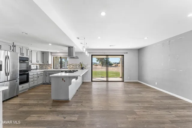 a large white kitchen with a refrigerator a sink dishwasher and a stove with wooden floor