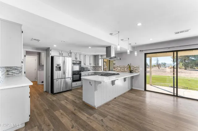 a large kitchen with kitchen island a large counter top space a sink stainless steel appliances and cabinets