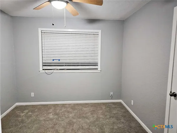 an empty room with a window and a fan