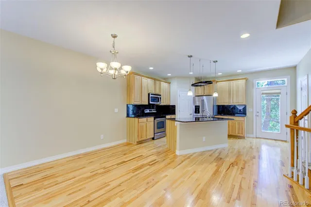 a living room with kitchen island dining table wooden floor and a kitchen view