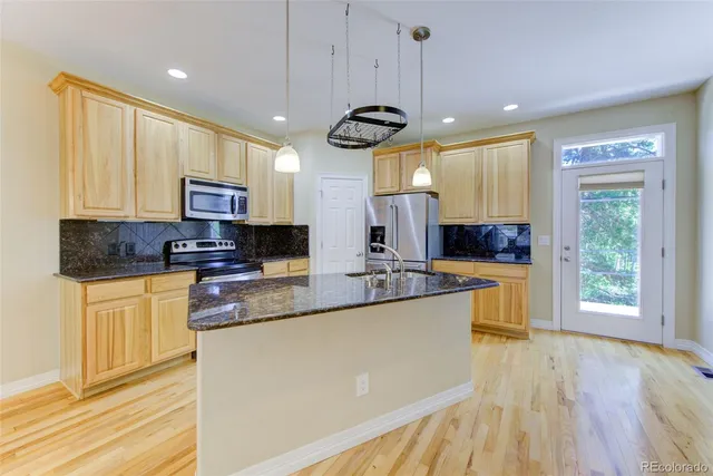 a kitchen with stainless steel appliances granite countertop a sink a stove top oven a counter space and cabinets